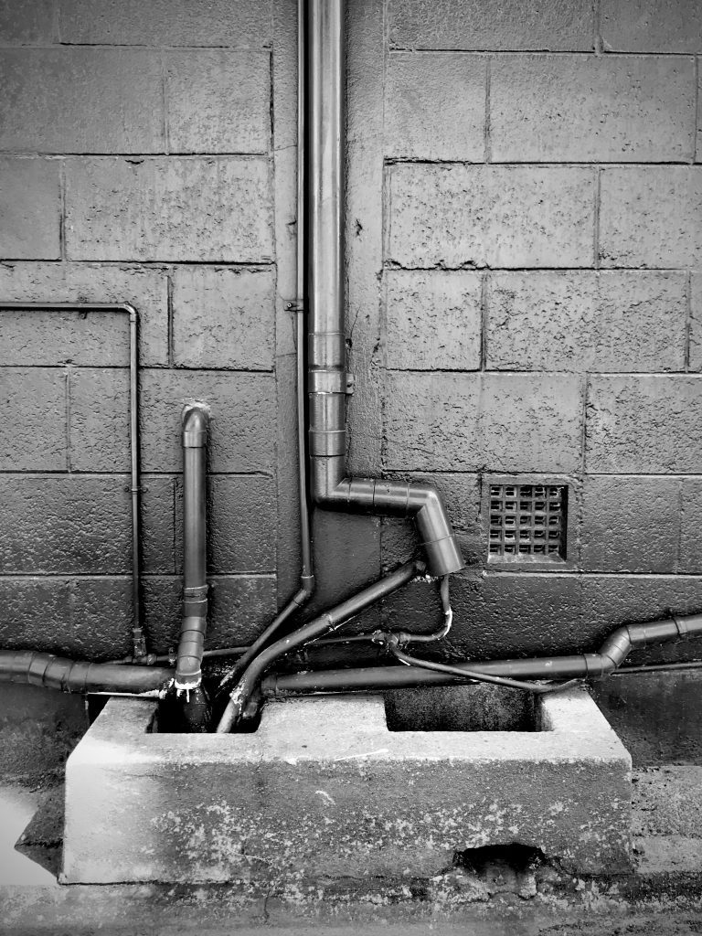 A black and white photograph of pipes running into a drain