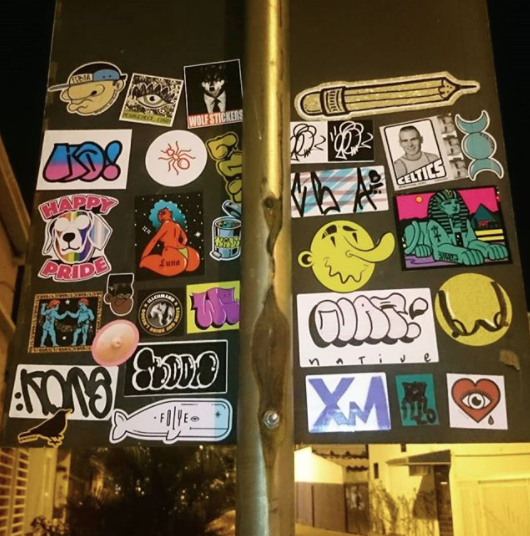 An array of stickers on a street sign in Brazil