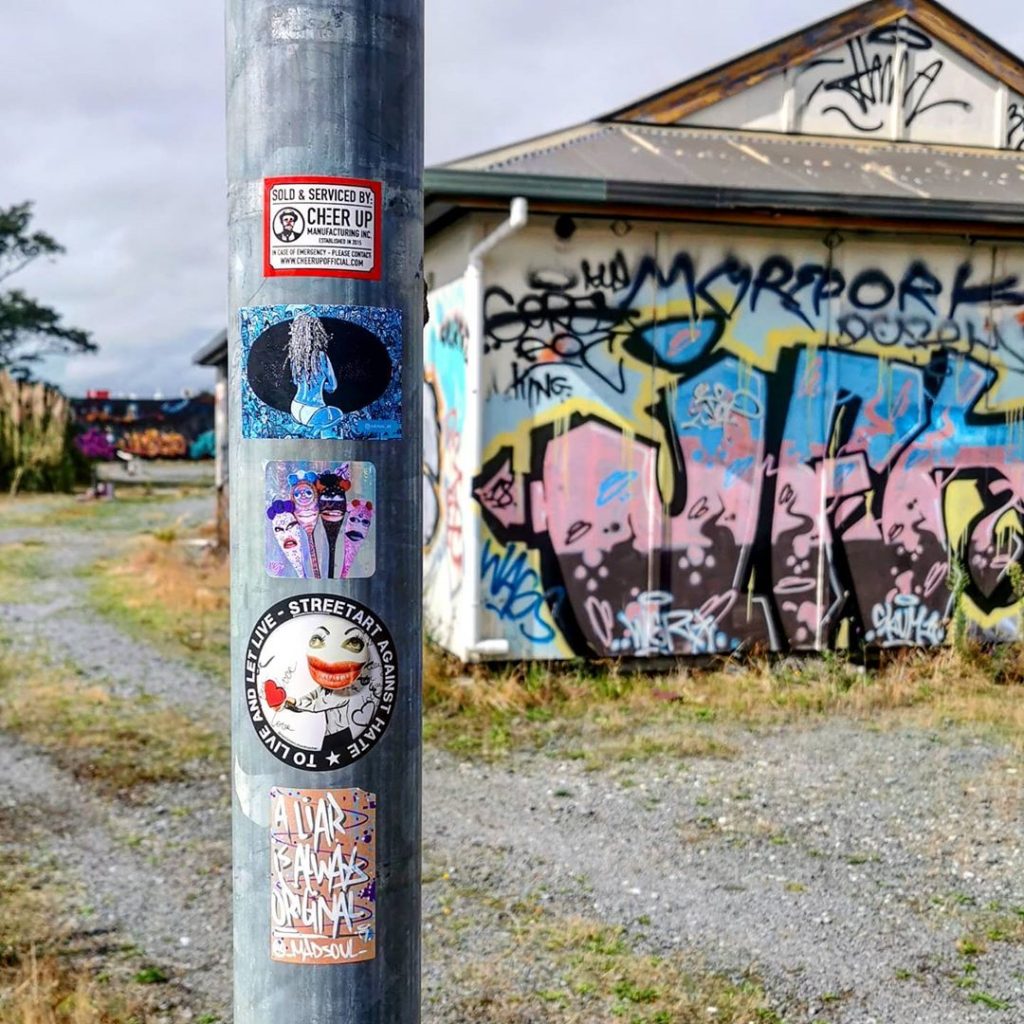 Stickers on a lamppost near the graffitied railway tracks in Christchurch