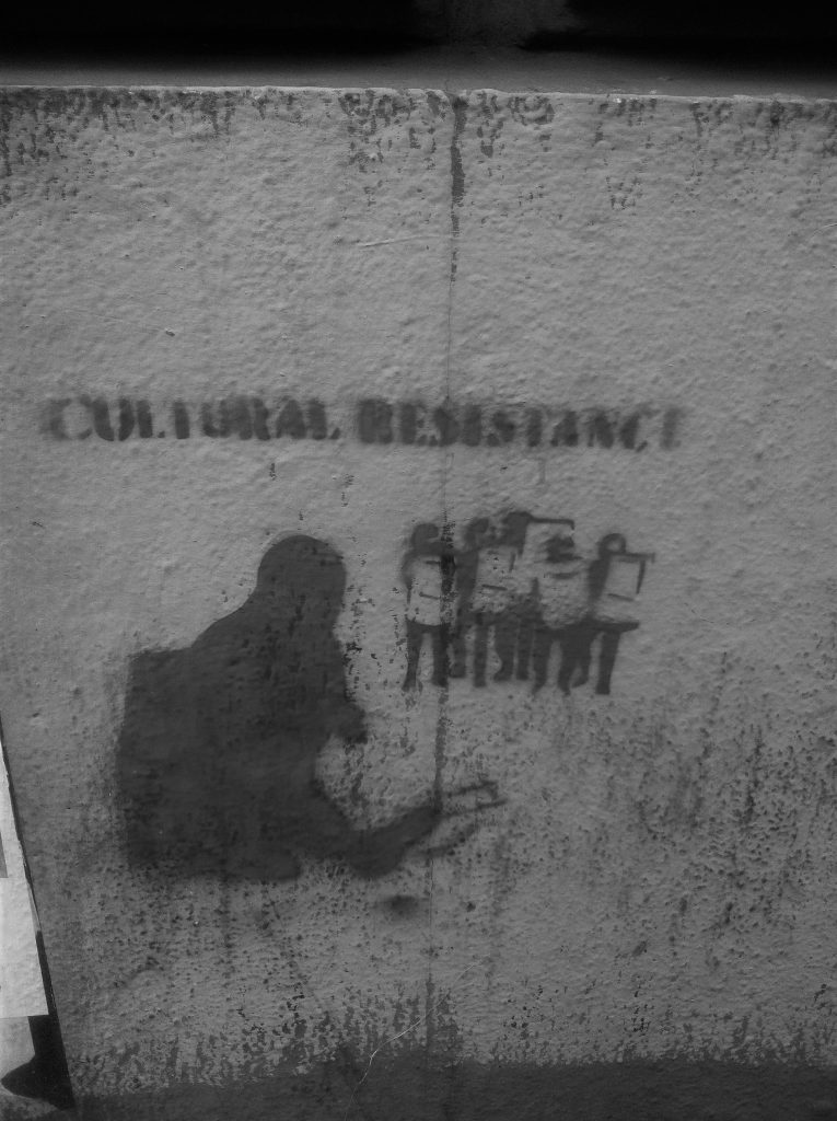 A crowd of protestors are stencilled on a wall under the words Cultural Resistance