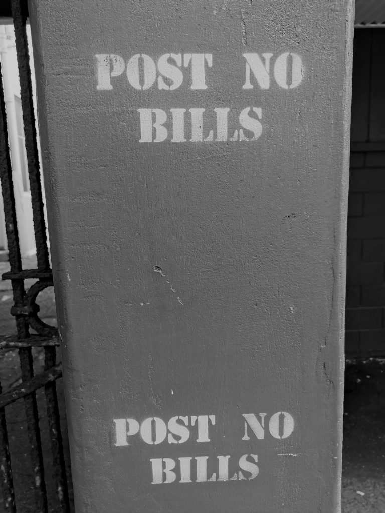 the instruction to Post No Bills is stencilled on a concrete pillar