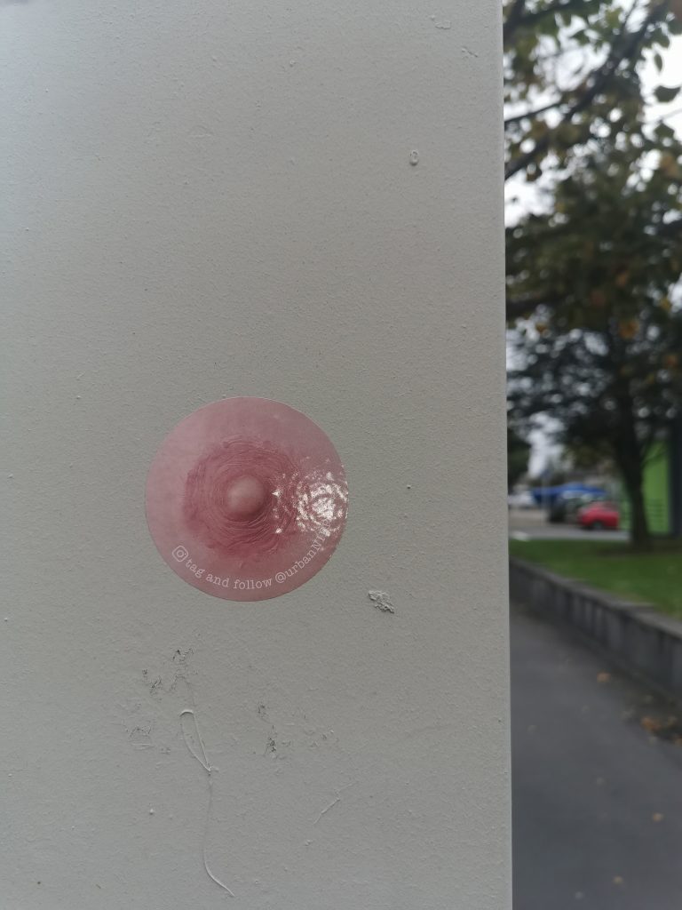 A sticker of a nipple is stuck to a lamppost