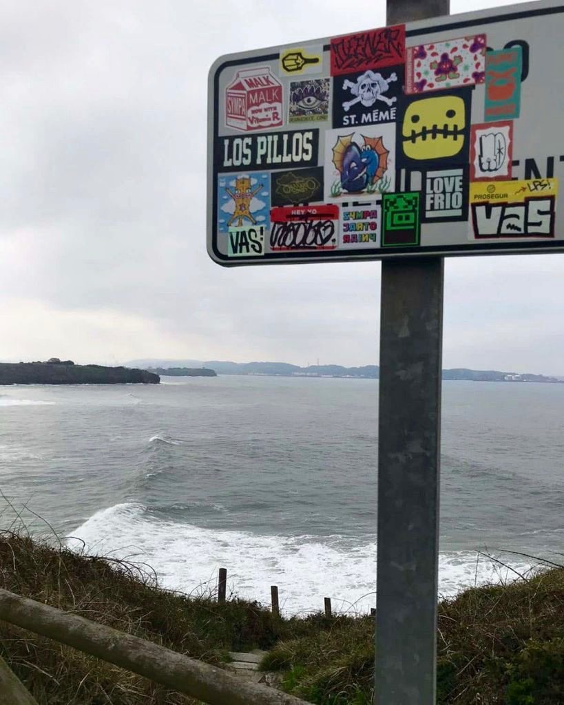 Stickers on the freverse of a sign overlooking the ocean in Spain