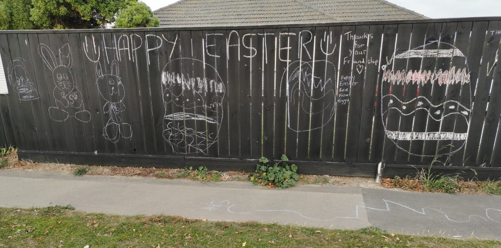 A suburban fence is adorned with an Easter message in chalk.